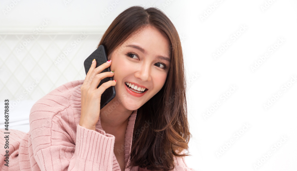 Portrait of smiling happy beautiful asian woman relaxing using technology of smartphone.Young asian girl talking on the phone with friend and lying on bed at home.technology and communication concept Portrait of smiling happy beautiful asian woman relaxing using technology of smartphone.Young asian girl talking on the phone with friend and lying on bed at home.technology and communication concept