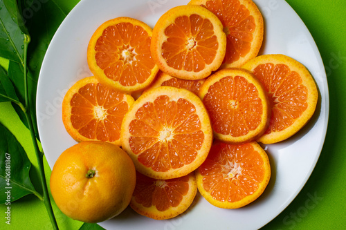 cut oranges on a white plate with green background