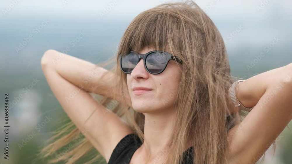 Portrait of a young woman in dark sunglasses relaxing outdoors on a windy summer day. Portrait of a young woman in dark sunglasses relaxing outdoors on a windy summer day.