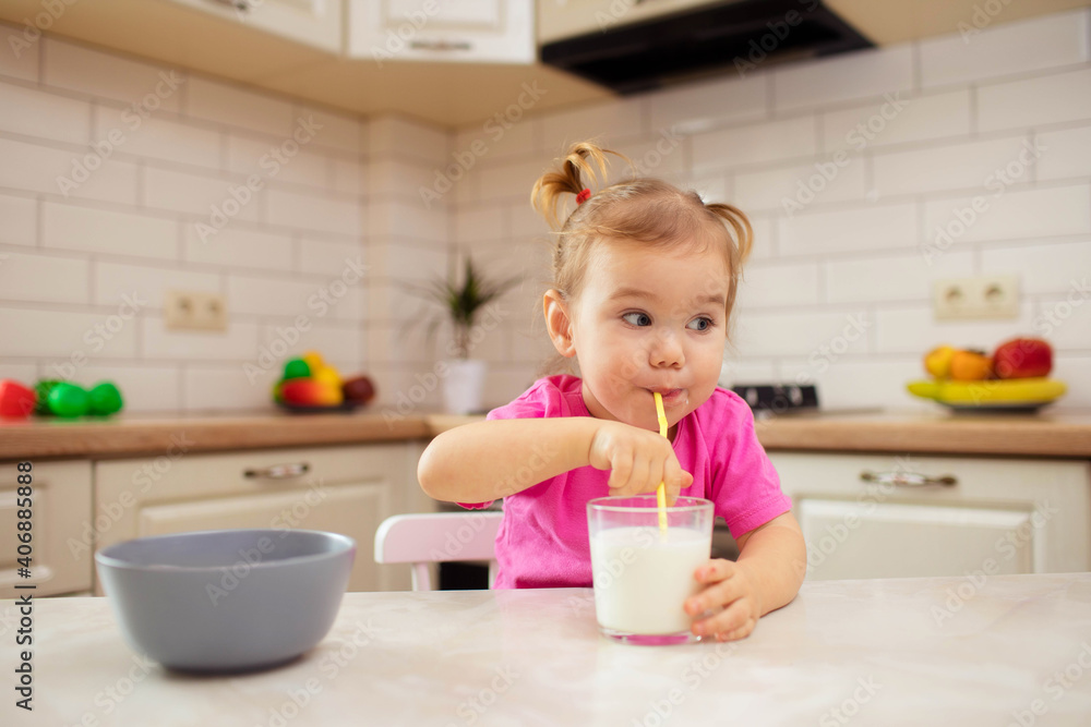 happy baby sitting at the table in the kitchen and eating with an appetite happy baby sitting at the table in the kitchen and eating with an appetite