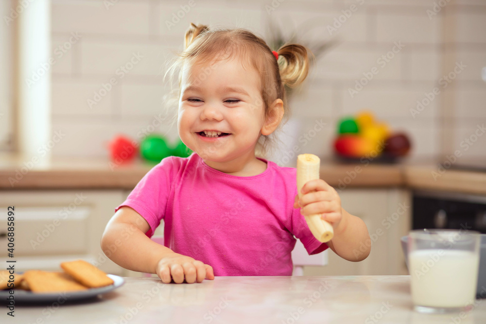 happy baby sitting at the table in the kitchen and eating with an appetite happy baby sitting at the table in the kitchen and eating with an appetite