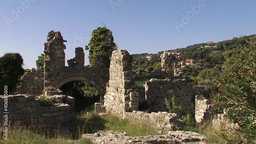 Walls of the old stone fortress with arch and trees on a bright day photo