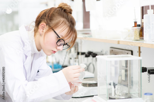In a chemical laboratory, a girl laboratory assistant weighs a chemical in powder on a special scale. Assistant in the chemistry laboratory at the university