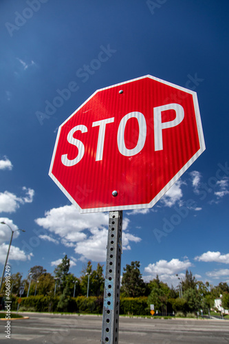 Bright red new stop sign isolated against blue sky and clouds