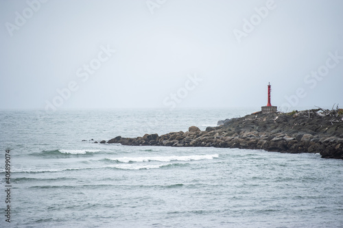lighthouse on the island off shore rocks waves crashing