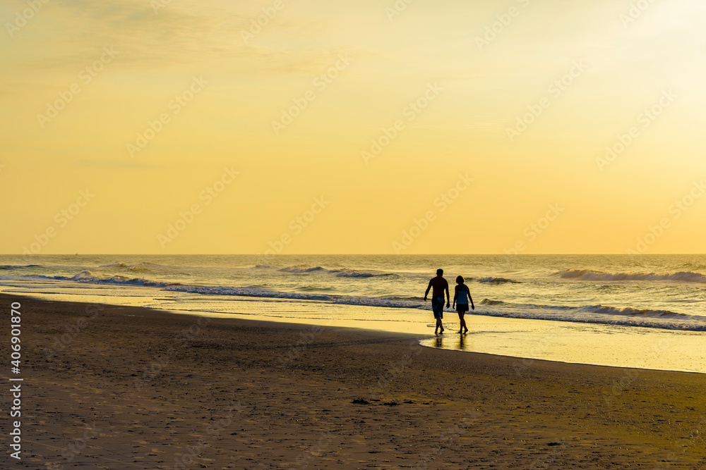 Couple walking on the beach at sunrise