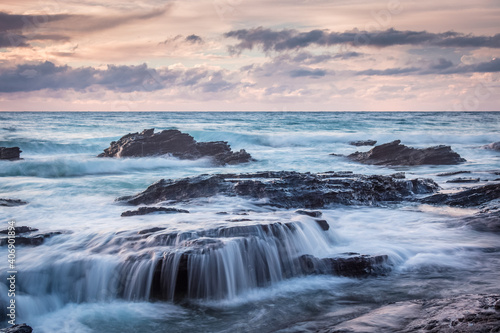 Waves across the rocks in the sunrise