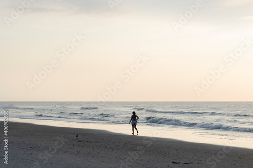 Women walking alone on the beach at sunset