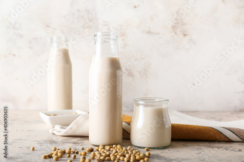 Bottles of tasty soy milk on light background