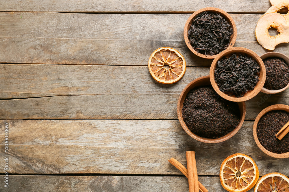 Bowls with dry black tea leaves, spices and dried fruits on wooden background Bowls with dry black tea leaves, spices and dried fruits on wooden background