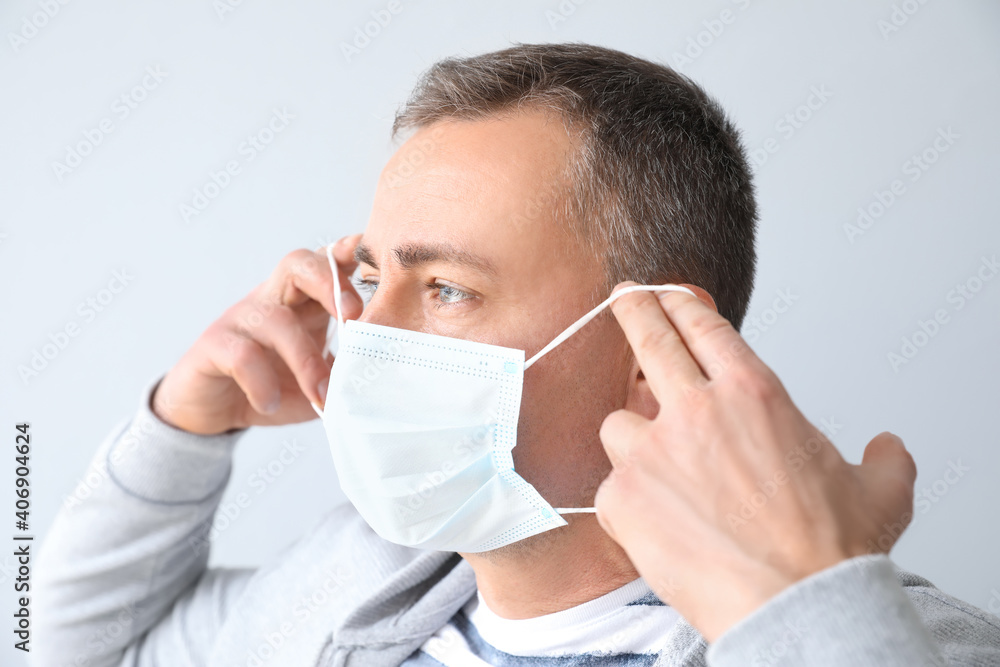 Mature man wearing medical mask on grey background Mature man wearing medical mask on grey background