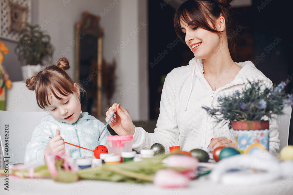 Fototapeta premium Mother and daughter paint eggs. Family in a kitchen. Preparing for Easter