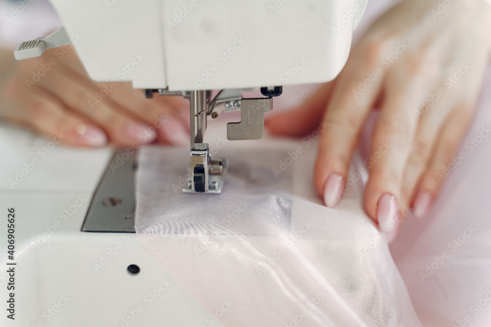 Woman use sewing machine. Designes sew cloth. Blonde in studio.