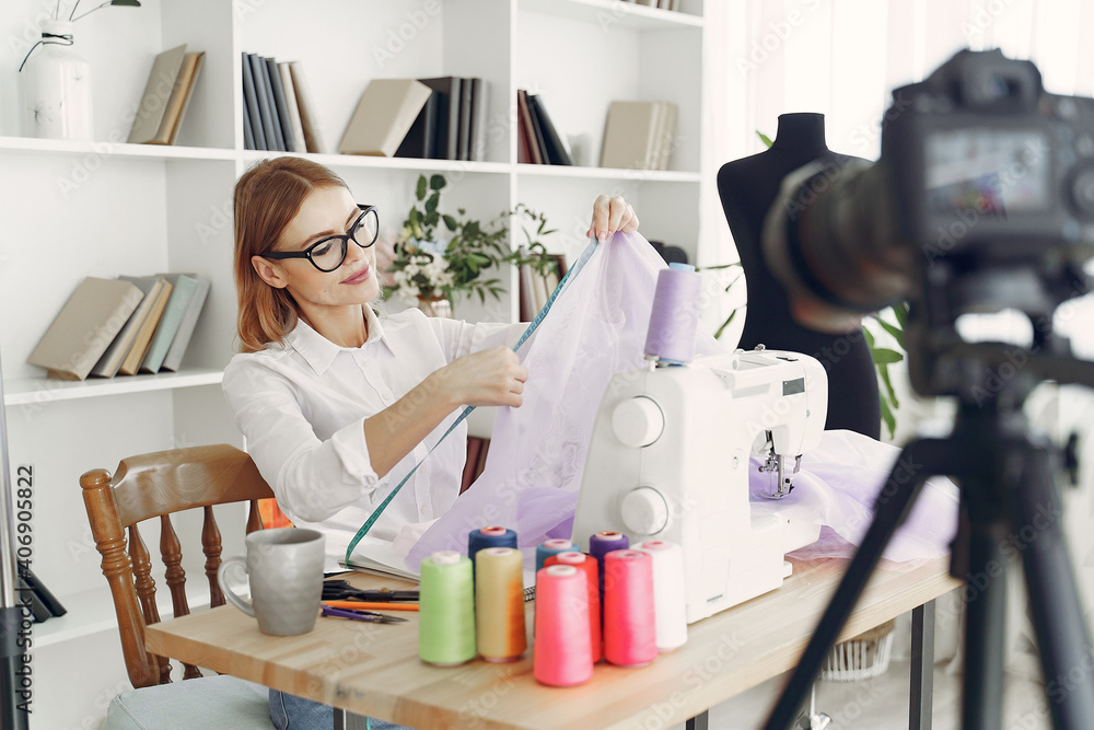 Woman use sewing machine. Designes sew cloth. Blonde in studio. Woman shoots a blog. Woman use sewing machine. Designes sew cloth. Blonde in studio. Woman shoots a blog.