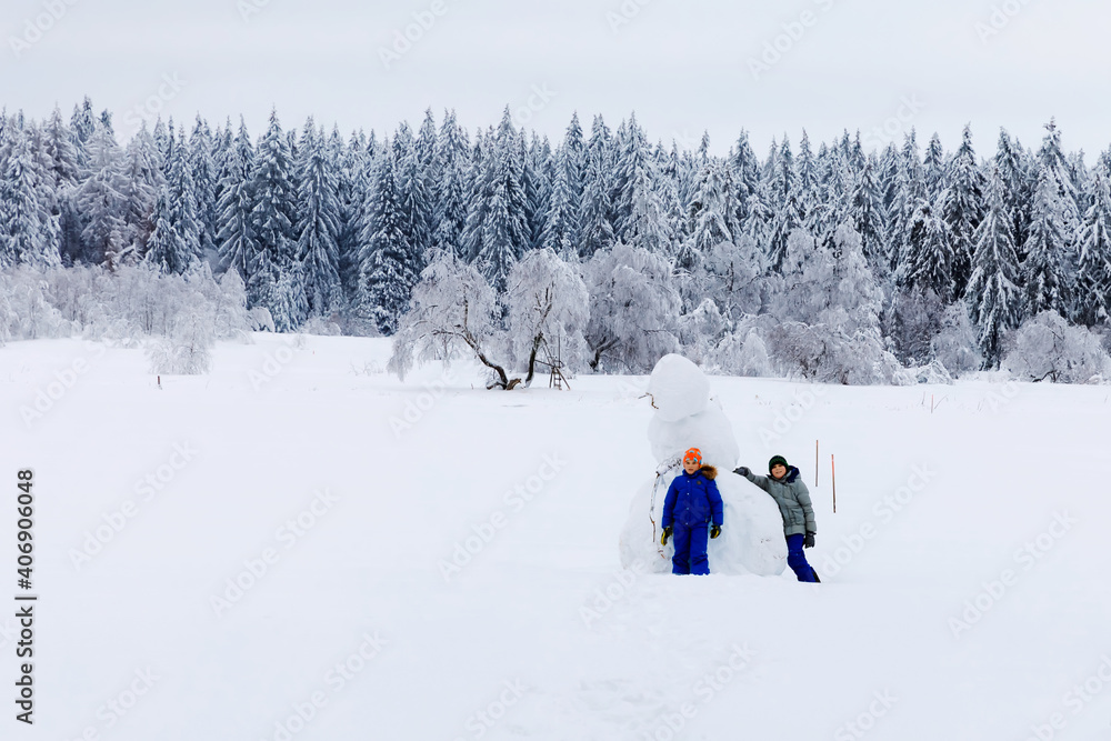 Two school kid boy walking in snowy winter forest. Happy children having fun outdoors in winter. Family, siblings and brothers hiking and walking together, outdoors. Active leisure with kids