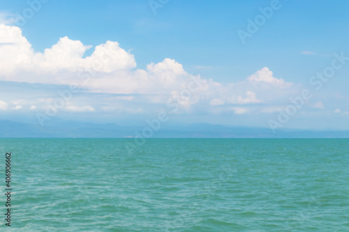 Beautiful white clouds on blue sky over calm sea with sunlight reflection.