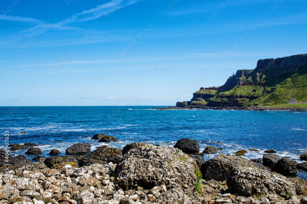 Landscape of Giant's Causeway trail with a blue sky in summer in Northern Ireland, County Antrim. UNESCO heritage. It is an area of basalt columns, the result of an ancient volcanic fissure eruption