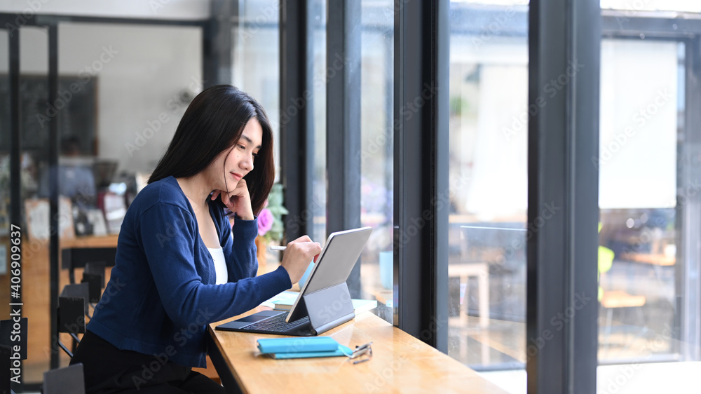 Cheerful young female freelancer working with tablet computer at comfortable workstation. Cheerful young female freelancer working with tablet computer at comfortable workstation.