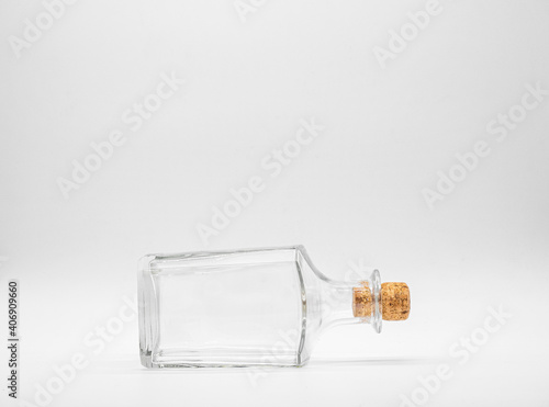 Empty glass bottle closed with cork cap isolated on a white background. Front view of the laying on its side transparent square bottle. photo