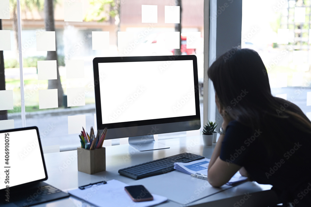 Rear view of businesswoman or office worker working with computer while sitting in modern office. Rear view of businesswoman or office worker working with computer while sitting in modern office.