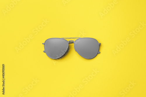 Gray painted sunglasses on yellow background top view