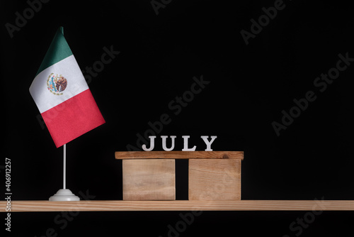 Wooden calendar of July with Mexico flag on black background. Holidays of Mexico in July