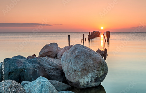 Coastal landscape with remains old broken pier and migrating birds on wooden ...