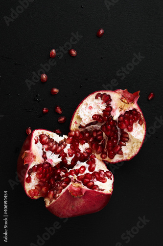 breaking pomegranate in half on black background