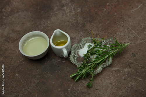 Olive and sunflower oil in small baskets, salt and rosemary, thyme on a granite table. ingredients for salad dressing