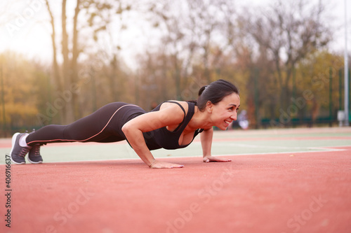 Happy girl doing plank outdoor on playground. Healthy lifestyle. Morning workout positive emotion smiling sportive people