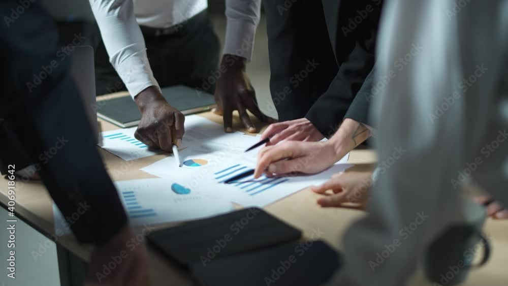 Business meeting, international management team at work, team is standing next to a work table and works with documents, discussing work plans and planning financial statistics, brainstorm, slow Business meeting, international management team at work, team is standing next to a work table and works with documents, discussing work plans and planning financial statistics, brainstorm, slow