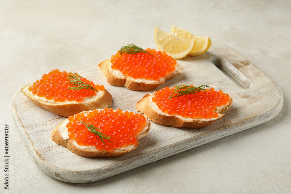 Wooden board with sandwiches with red caviar on white textured background Wooden board with sandwiches with red caviar on white textured background