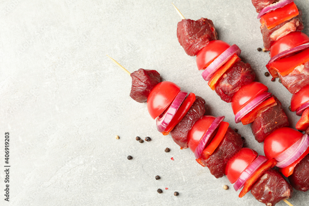 Skewers with raw shish kebab on gray background Skewers with raw shish kebab on gray background