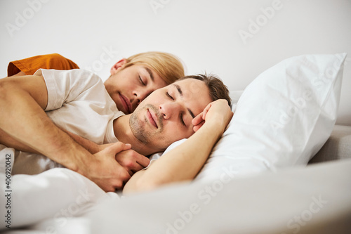 Loving gay couple sleeping and cuddling in bed