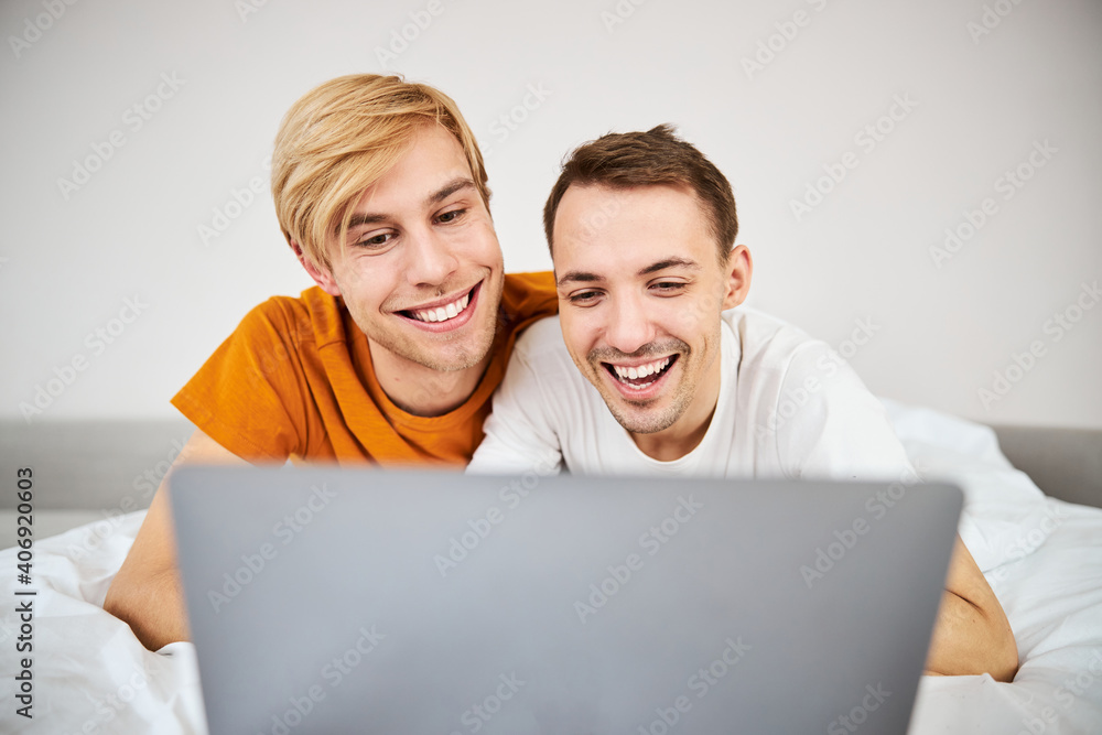 Happy homosexual couple watching movie together on laptop
