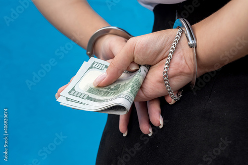 female hands in handcuffs holds money