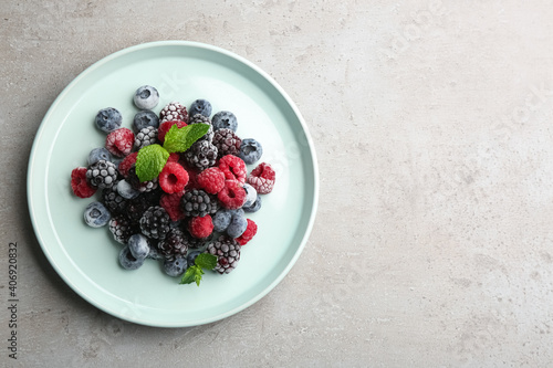 Mix of different frozen berries on grey table, top view. Space for text