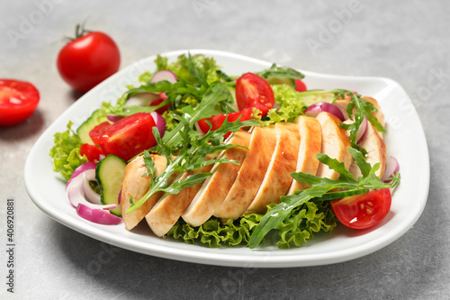 Delicious salad with meat, arugula and vegetables on grey table, closeup