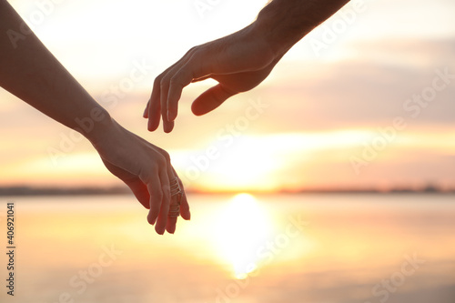 Man and woman reaching hands to each other at sunset, closeup. Nature healing power