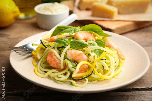 Delicious zucchini pasta with shrimps and basil on wooden table, closeup