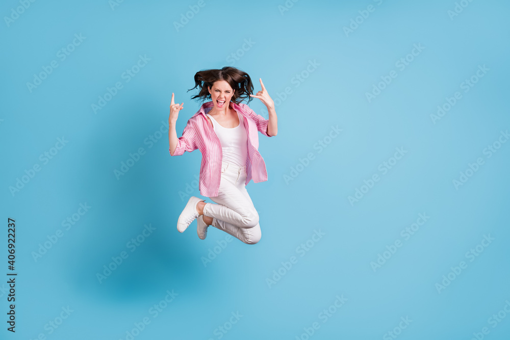 Full body portrait of joyful person jump show heavy metal sign open mouth isolated on blue color background Full body portrait of joyful person jump show heavy metal sign open mouth isolated on blue color background
