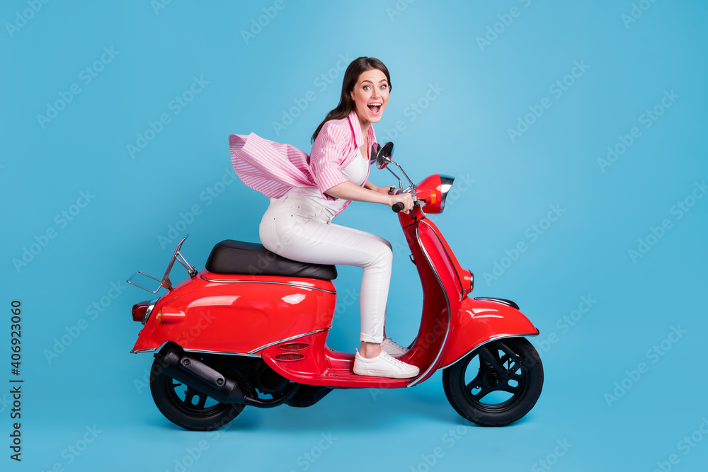 Full size side profile photo of attractive impressed person open mouth drive moped isolated on blue color background Full size side profile photo of attractive impressed person open mouth drive moped isolated on blue color background