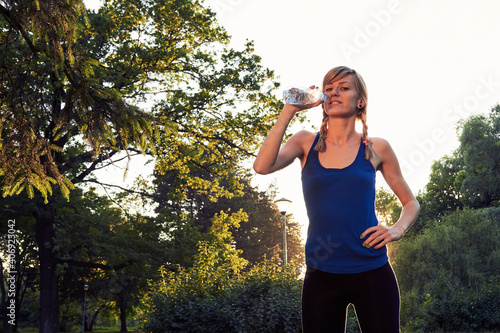 Sporty woman making pause after exercising in the park.