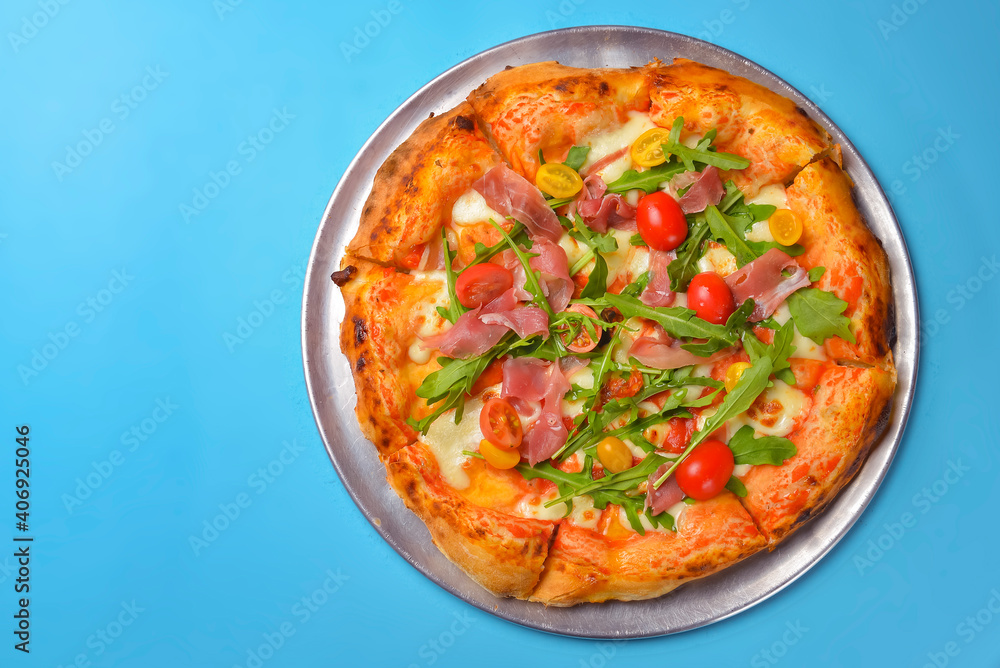 A Pepperoni pizza on a blue background isolated. Traditional Italian cuisine concept, pizza Margarita or Margherita A Pepperoni pizza on a blue background isolated. Traditional Italian cuisine concept, pizza Margarita or Margherita