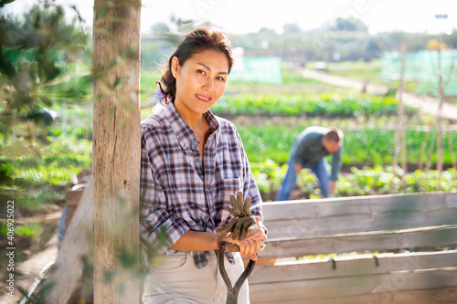 Portrait of kazah woman with gardening tools outdoors. Asian woman standing with shovel in her vegetables garden photo