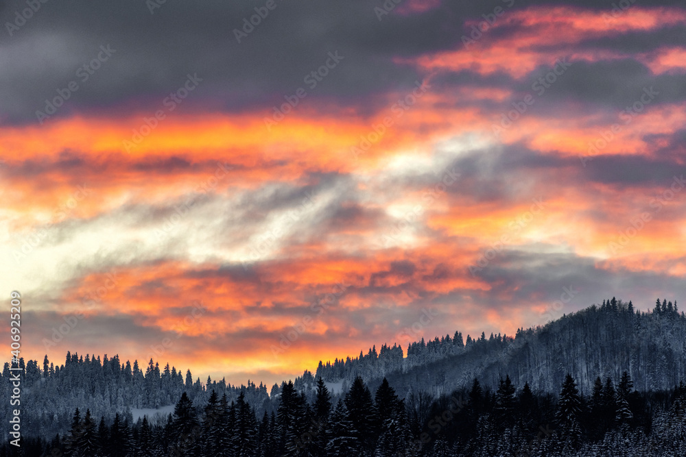 Colorful clouds on evening sky and winter mountains at background