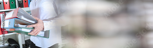 Businesswoman holding binders; panoramic banner