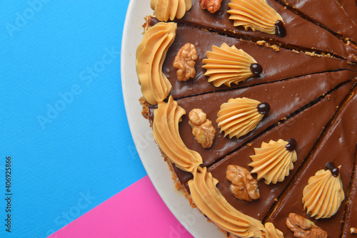 Chocolate cake with icing on top and with nuts over colorful background