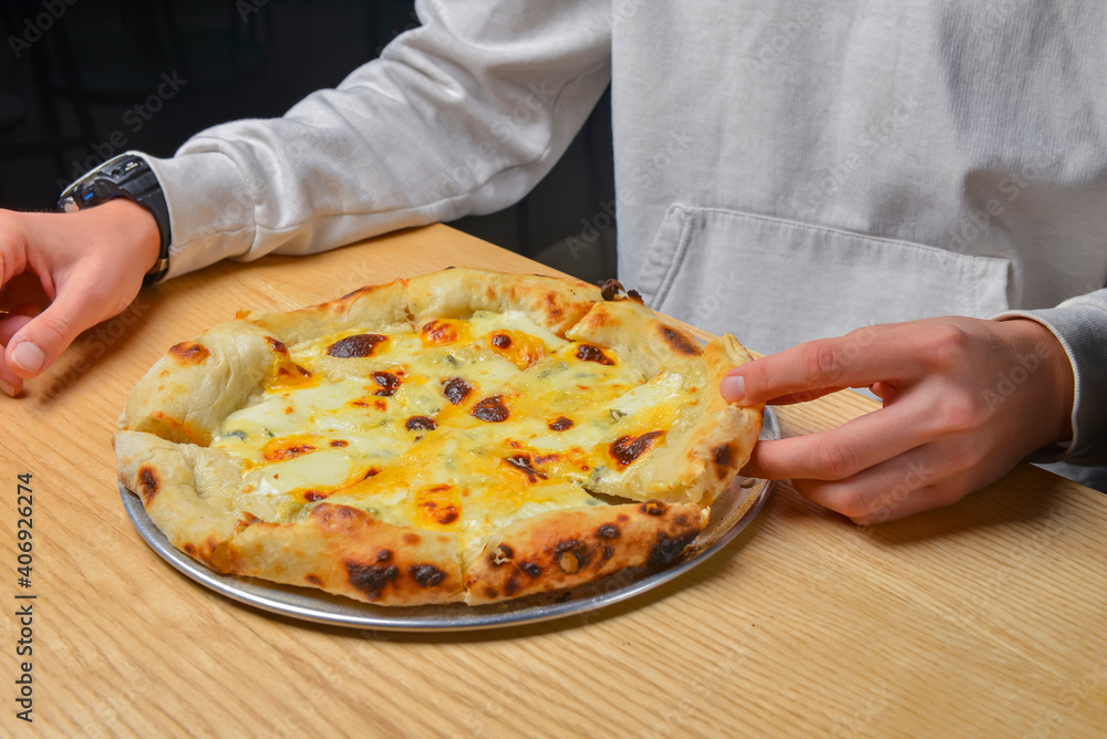 Young man eating a slice of pizza margherita. Still life, eating out concept. At restaurant or at home, pizza delivery.