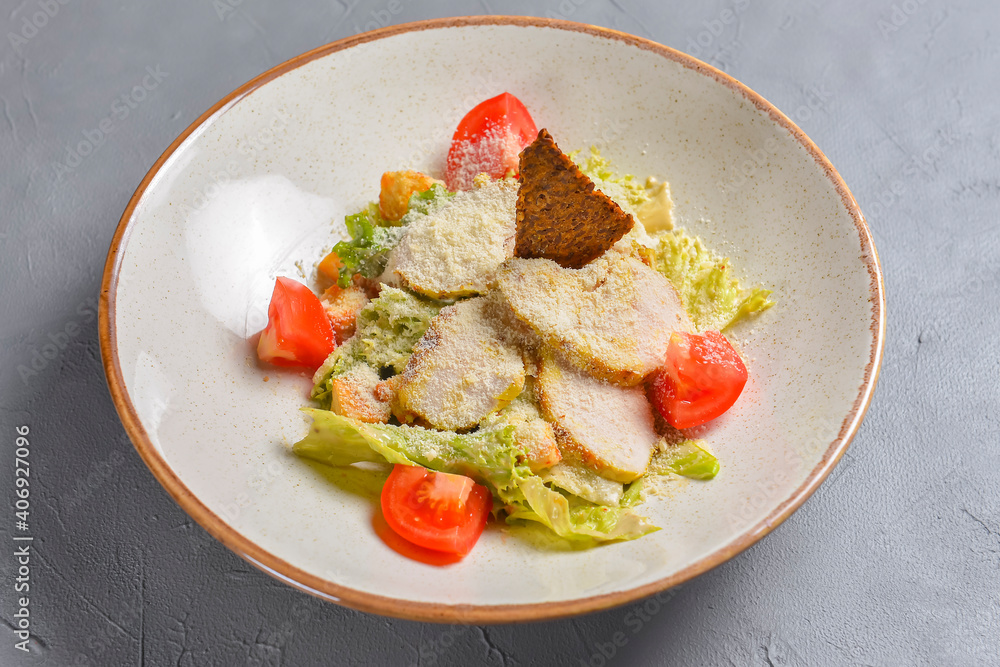 Bowl of Caesar Salad served on a black background in restaurant or diner. Traditional Caesar recipe